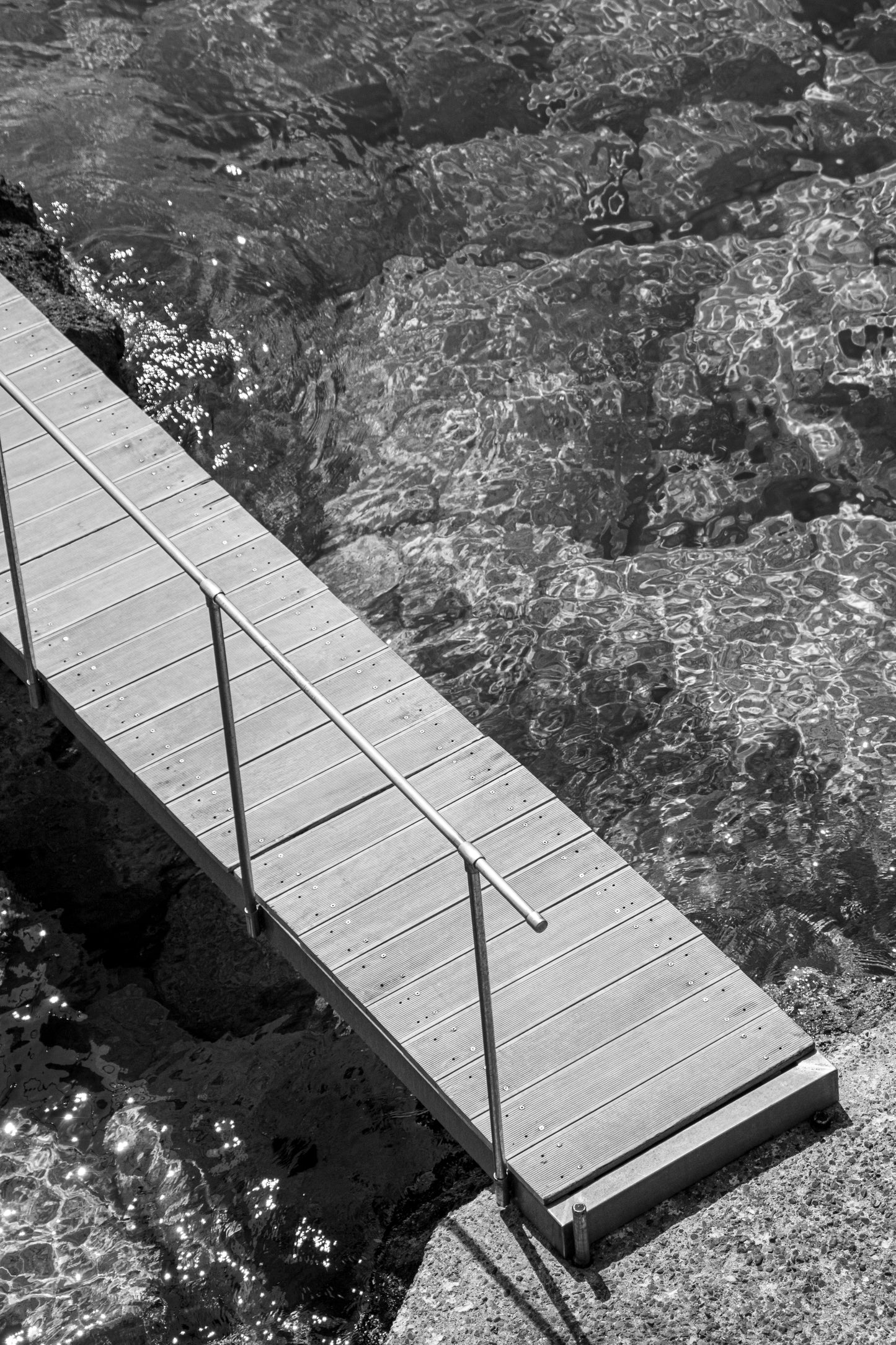 A solitary wooden pier extends over the shimmering waters, its planks aligned with precision,...