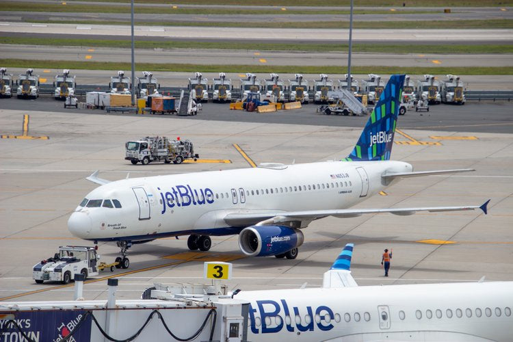 A jetBlue aircraft gracefully awaits its turn to soar, captured amidst the orchestrated chaos of an...