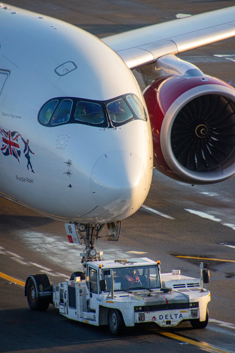 The image captures the poised elegance of a commercial aircraft being carefully towed by a ground...