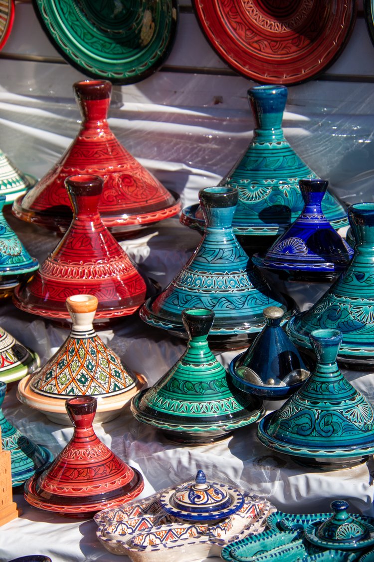 A vibrant array of Moroccan tagines captures the eye, each piece adorned with intricate patterns...