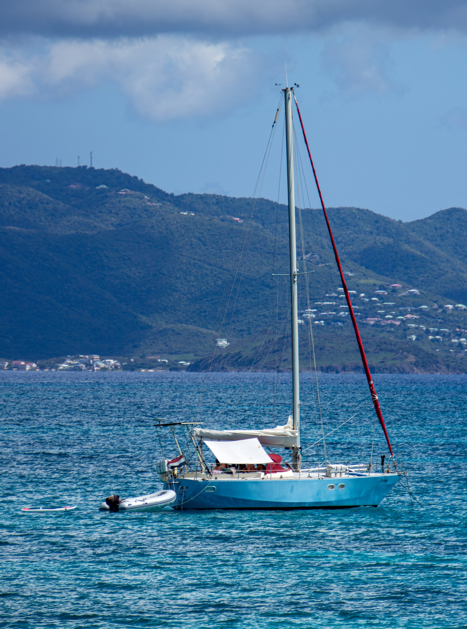 A lone sailboat rests peacefully on the azure waters, its mast slicing through the vivid blue sky