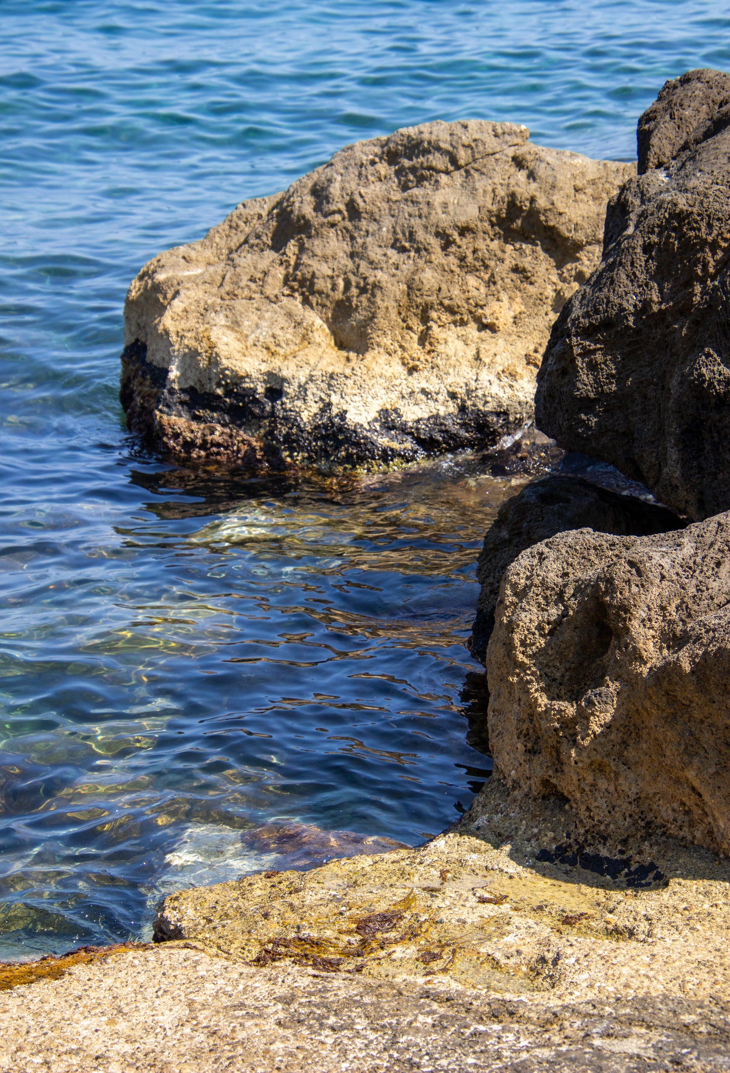 Sunlit rocks meet the shimmering Mediterranean Sea, creating a tranquil juxtaposition of textures...