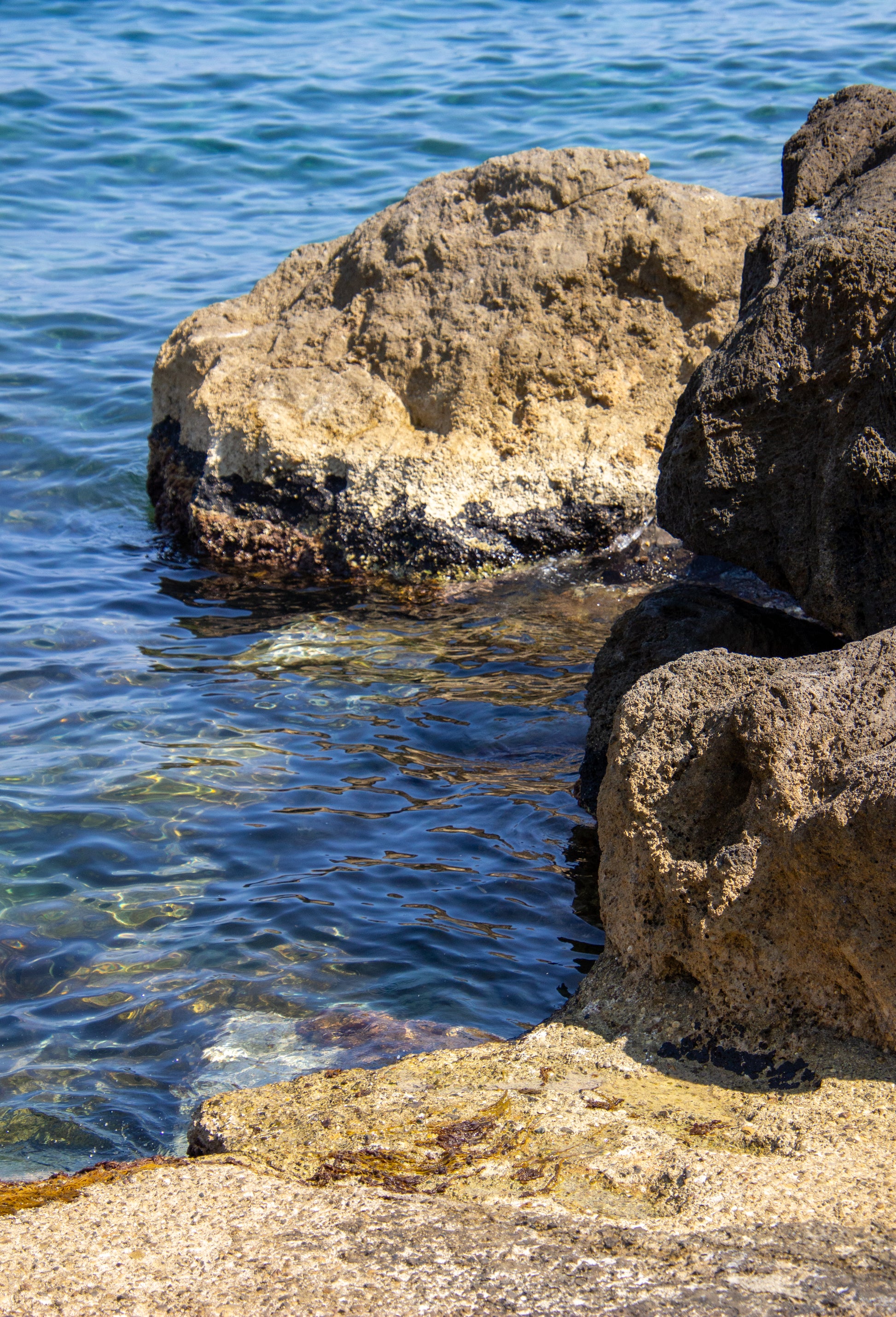 Sunlit rocks meet the shimmering Mediterranean Sea, creating a tranquil juxtaposition of textures...