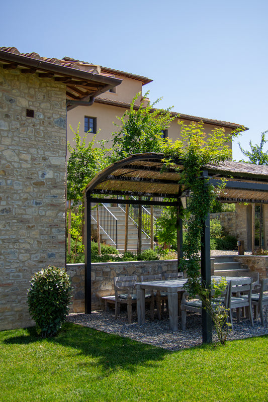 This serene image captures a sunlit corner of a Tuscan villa, where rustic stone walls meet lush...