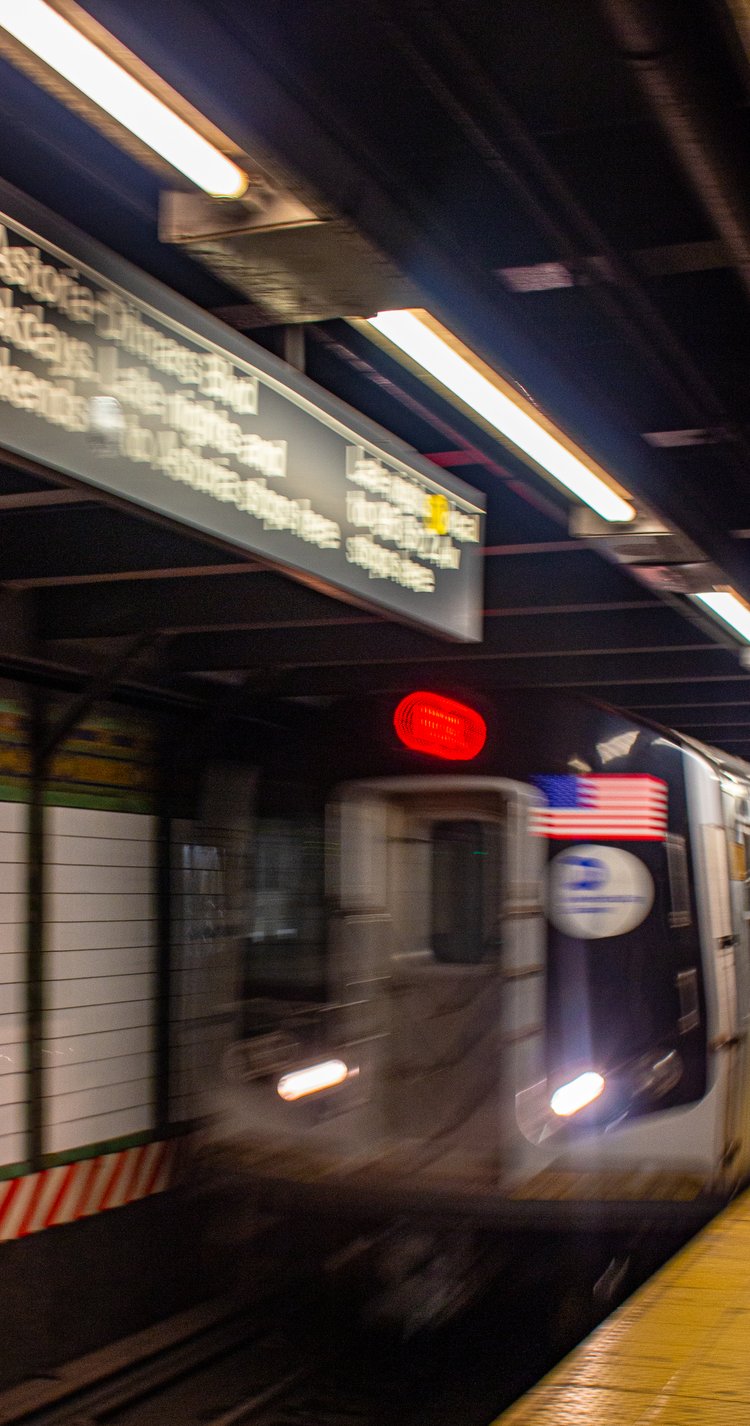 A subway train rushes through a dimly lit station, its motion a blur against the structured lines...